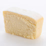 A single slice of vanilla baked cheesecake on a white background.