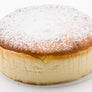 A round baked cheesecake dusted with icing sugar on a white background.